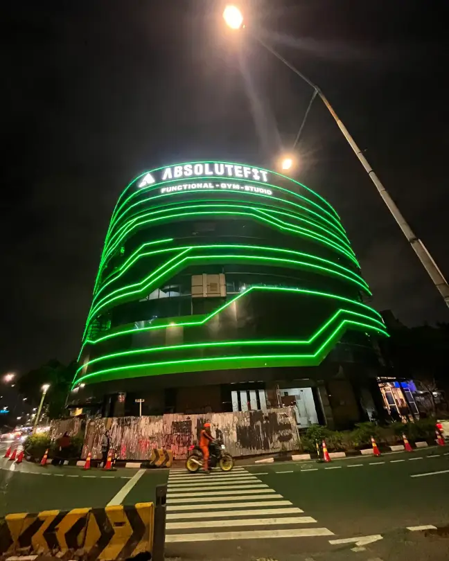 The AbsoluteFit building lit with green neon at night
